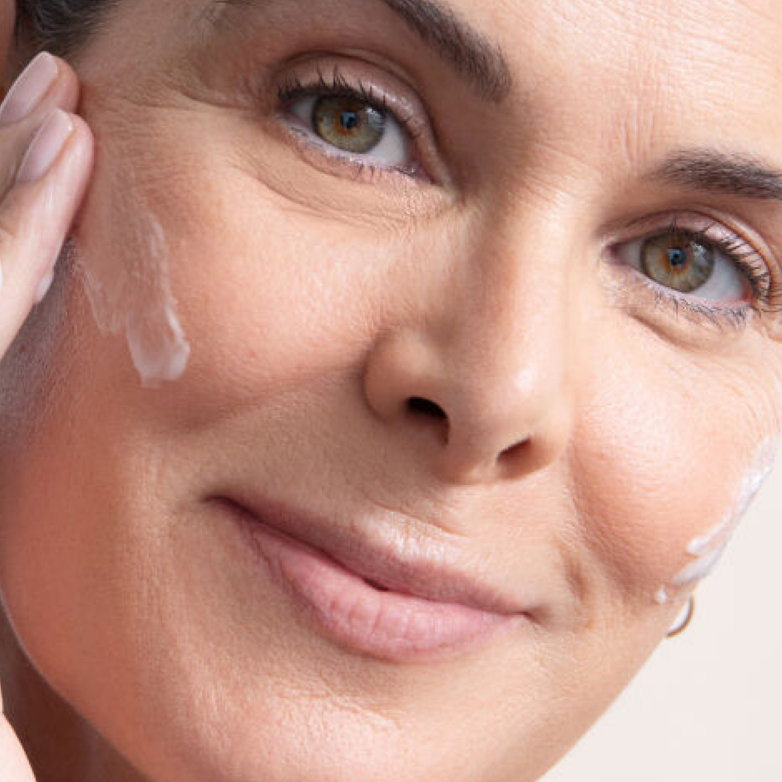Close-up of woman gently applying cream to her cheek.