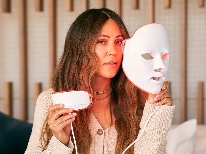 Shani holding the Déesse LED Mask and neck piece with the red light mode activated